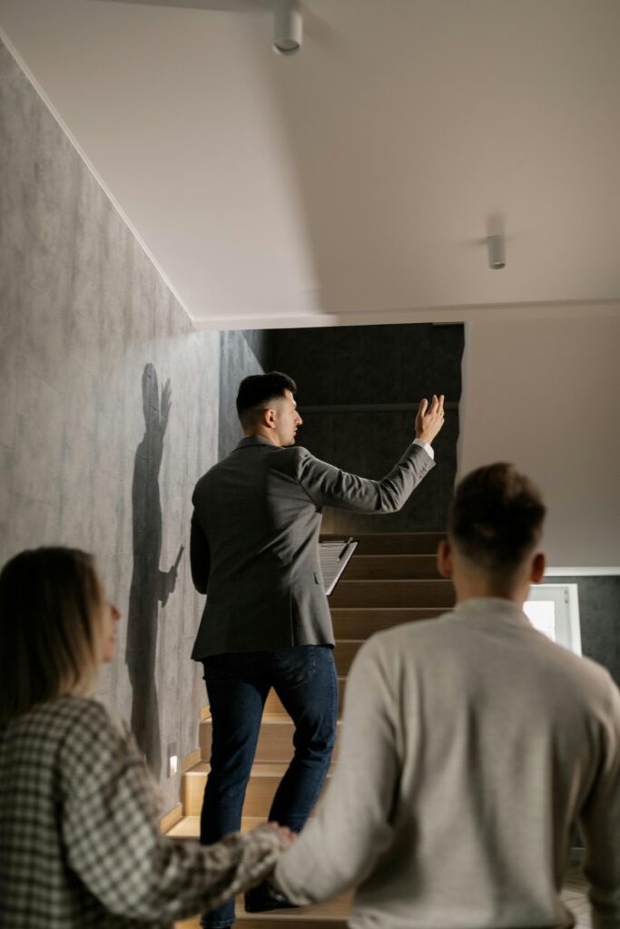 A real estate agent leads a couple on a house tour, highlighting interior features in a modern home.